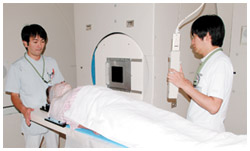 写真：回転ガントリー照射室で治療を受ける患者さんの位置合わせを行っているところ