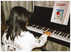 写真：自宅でピアノを弾く7歳のより子さん