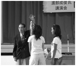 写真:生徒代表から花束と千羽鶴を渡され何度も「ありがとう」と言った