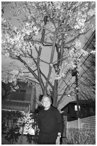 写真:桜の樹の下に立つ。タバコを口に得意のポーズで
