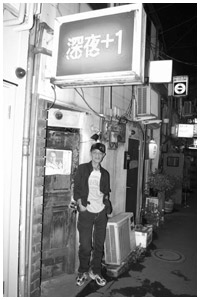 写真：新宿・ゴールデン街にある自分の店の前で