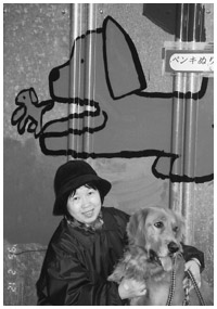 写真：発病後、愛犬モモと娘の描いた壁画の前で